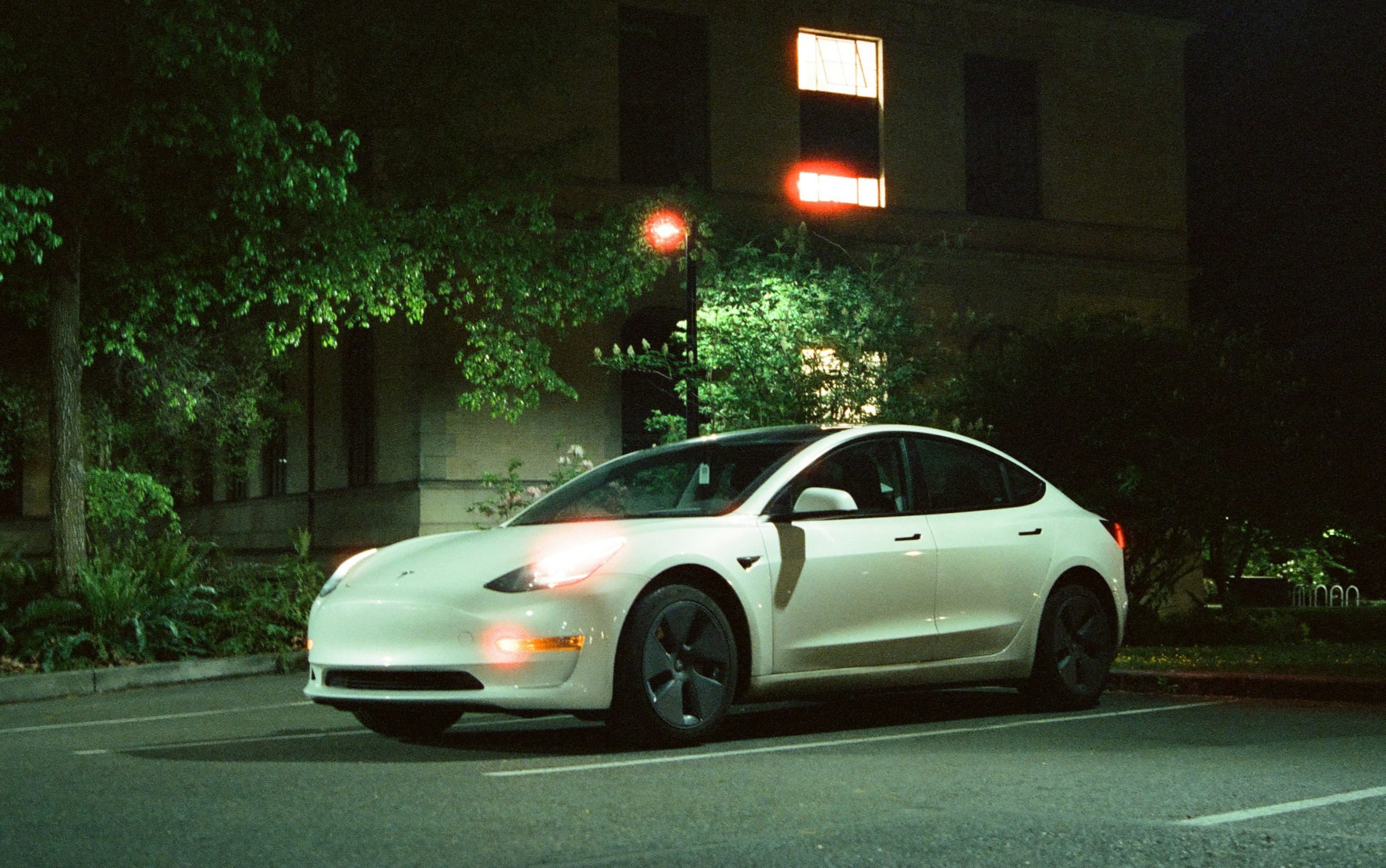 White Tesla parked at night beside building lights